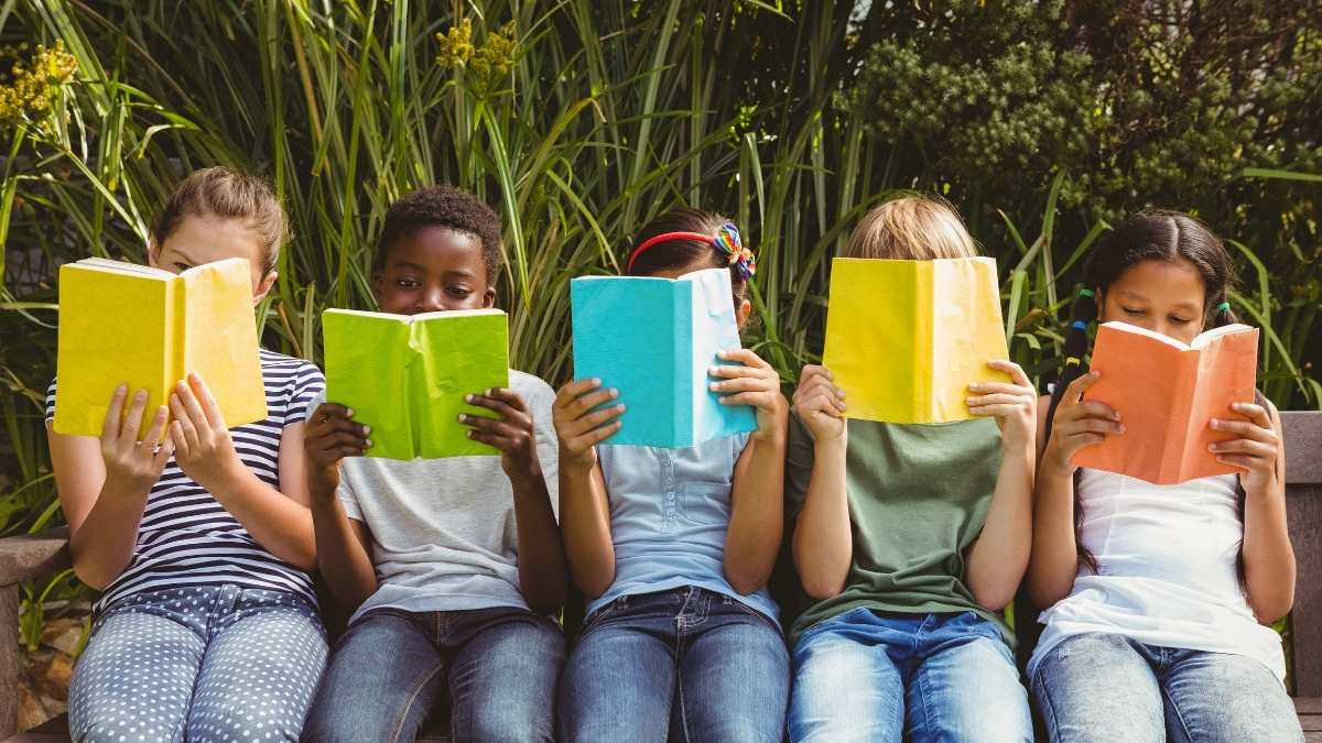 Des enfants en train de lire dans un parc
